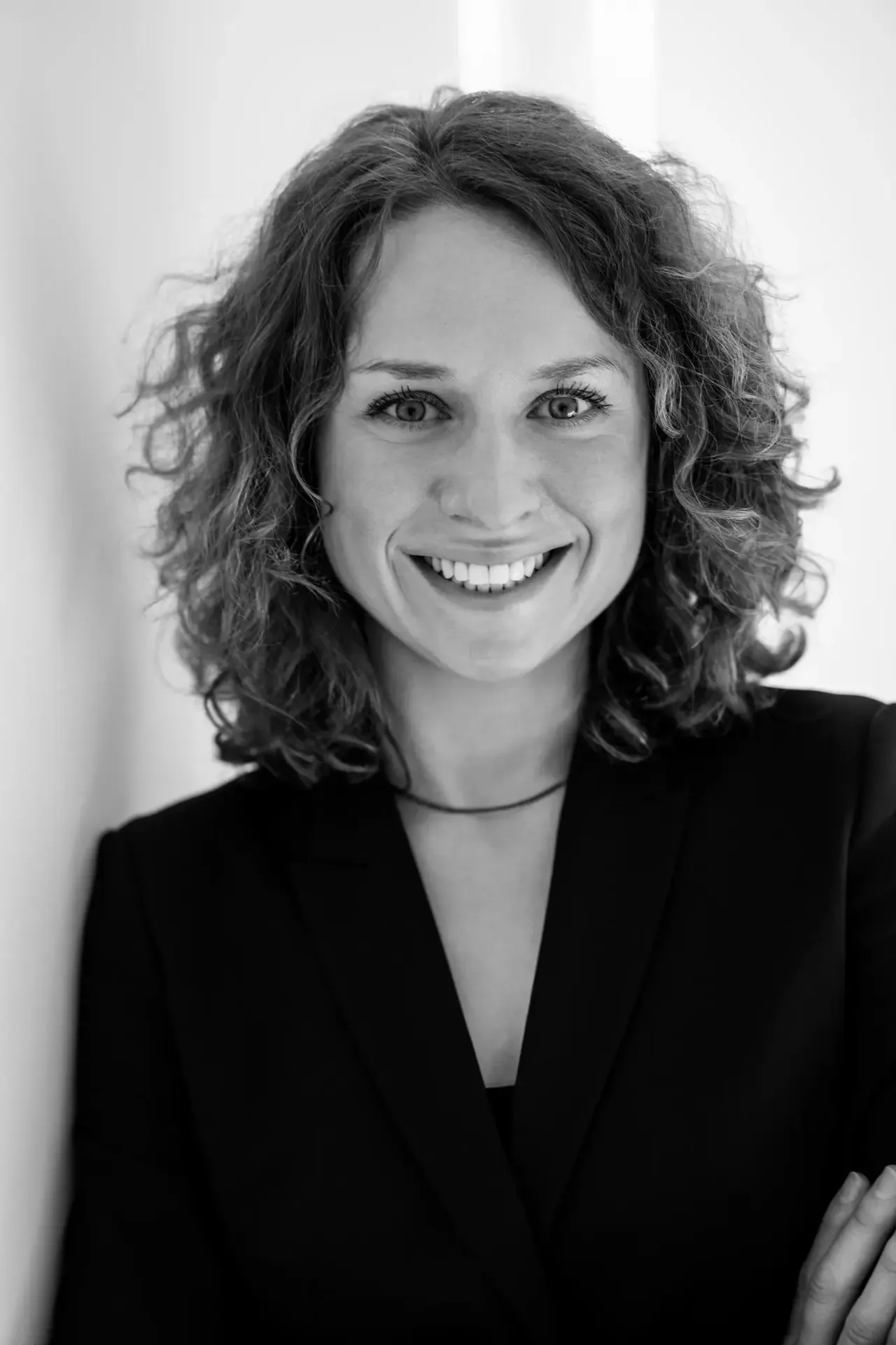 Schwarzweiß-Businessportrait einer Beraterin in Hamburg mit lockigem Haar und schwarzem Blazer für Website und LinkedIn