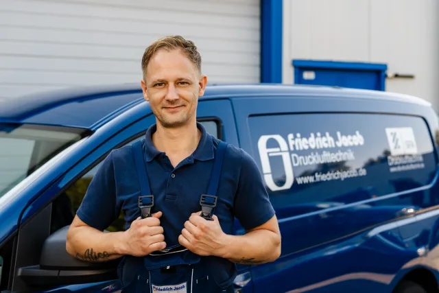 Mitarbeiterporträt Techniker mit Brille vor Firmenfahrzeug, konsistentes Licht