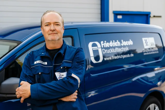 Mitarbeiterfoto Mitarbeiter mit Brille und Poloshirt vor Firmenwagen