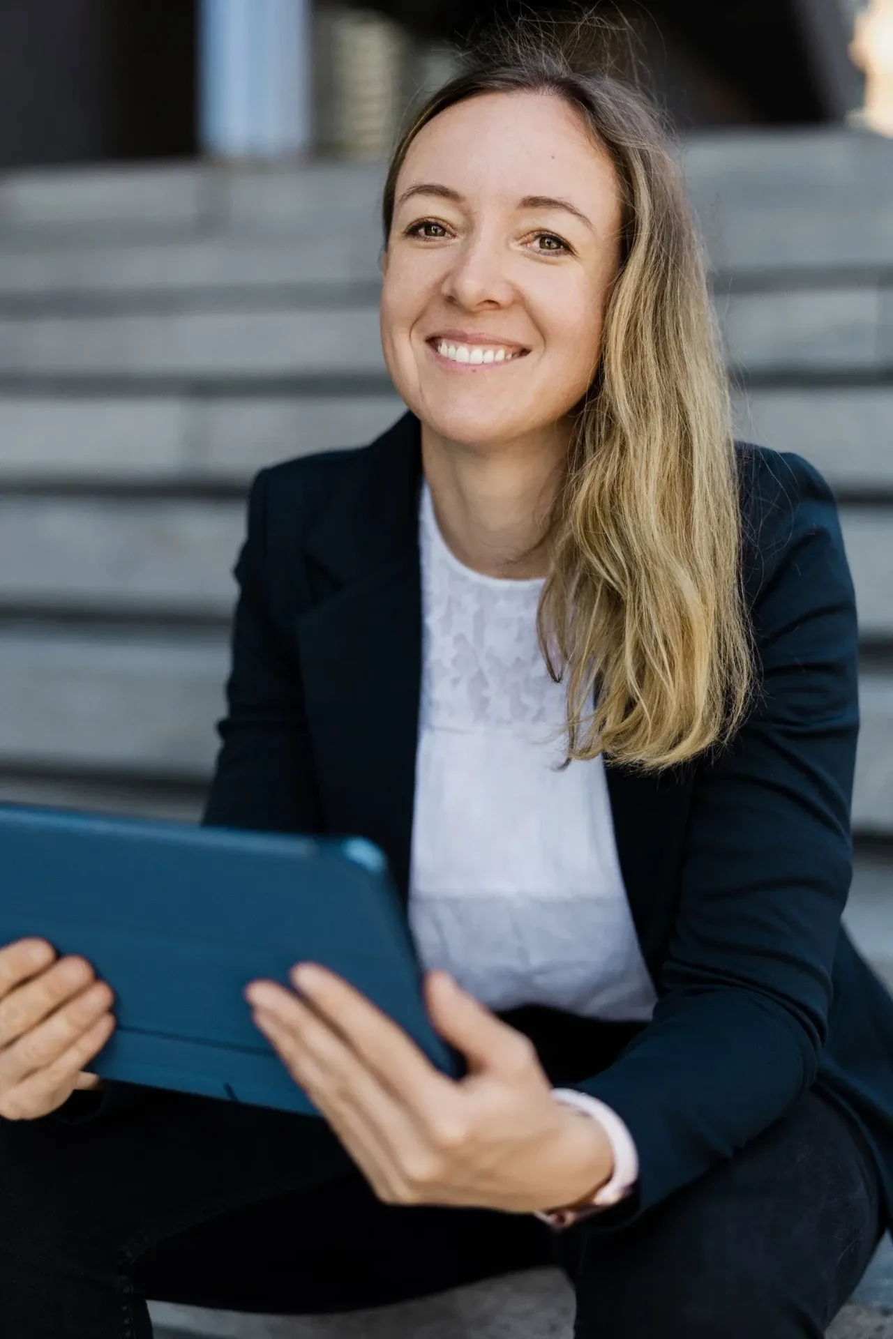 Personal Branding Fotografie Hamburg: lächelnde Unternehmerin mit Tablet auf einer Treppe – Bild für LinkedIn und Website